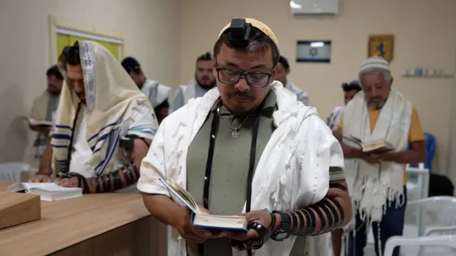 Homens com trajes ritualísticos judaicos durante oração em sinagoga