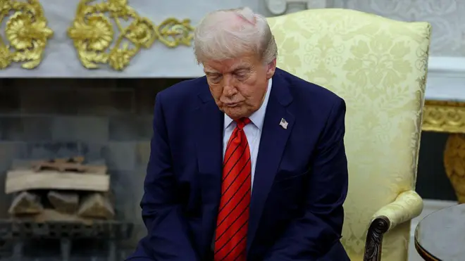 Дональд Трамп с грустным лицом сидит в Овальном кабинете и смотрит в пол