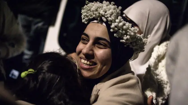 Una mujer palestina liberada de una cárcel israelí sonríe y abraza a una familiar