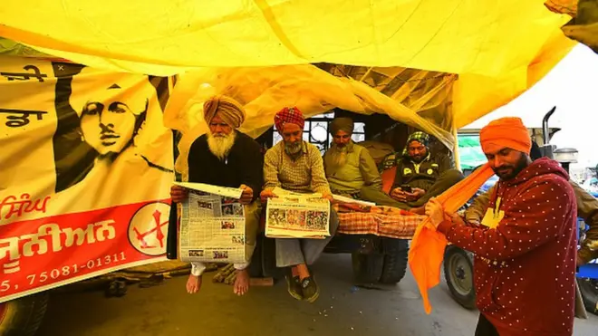 Demonstrators reading a newspaper at the Singhu border (Delhi-Haryana) protest site during the ongoing protest against new farm laws on December 22, 2020 near New Delhi, India.