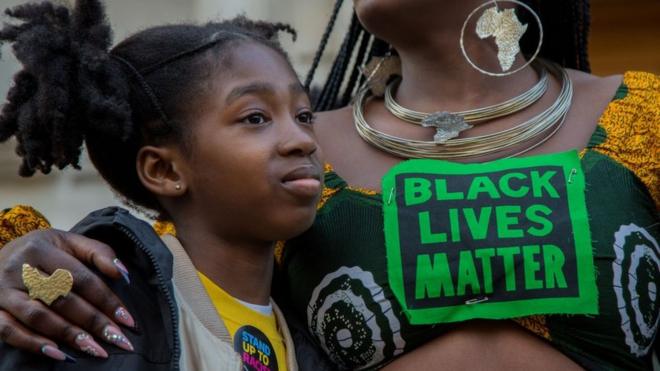 Una mujer con el mensaje "Las vidas negras importan" abraza a una niña en Londres durante una protesta el 20 de marzo de 2022.