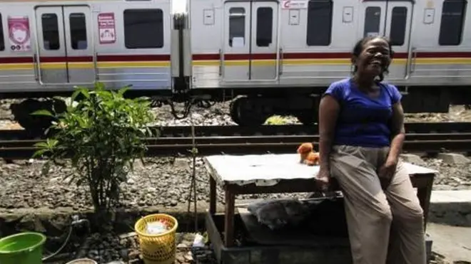 Seorang perempuan duduk di halaman rumahnya yang bersandingan dengan jalur kereta rel listrik (KRL) di Cideng, Ibu Kota Jakarta