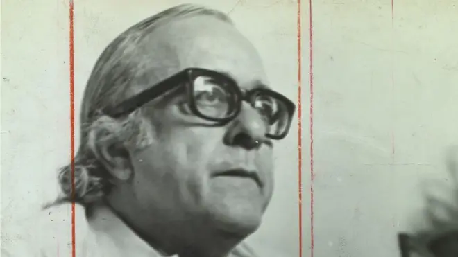 Foto em preto e branco mostra Vinicius de Moraes de perfil, de óculos, olhando sério para algo