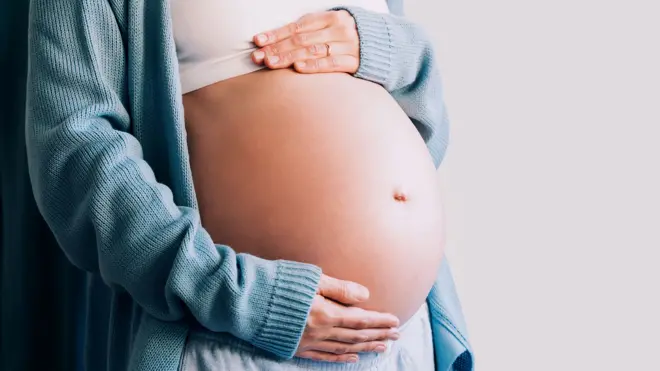 A stock image of an expectant mother touching her baby bump.