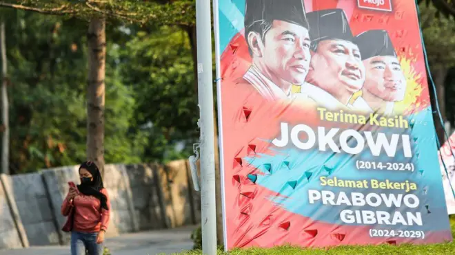 Seorang warga berjalan di samping spanduk bertuliskan ucapan terima kasih Jokowi, selamat bekerja Prabowo-Gibran di Jalan Sudirman, Jakarta, Jumat (18/10). 