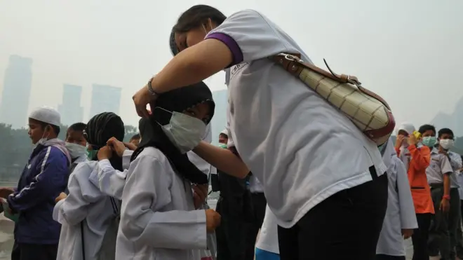 Seorang petugas memasang masker kepada seorang bocah di Kuala Lumpur, Malaysia, 23 Juni 2013, ketika kabut asap melanda wilayah itu akibat kebakaran hutan di wilayah Indonesia.