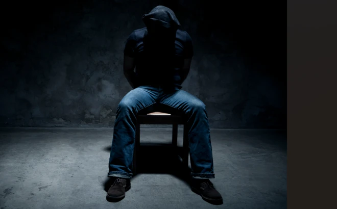 Ọkùnrin tó da aṣọ bojú tí wọ́n fi sínú yàrá dúdú