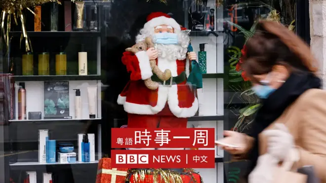 法國里爾一位女士走過擺放了聖誕老人像的商店櫥窗，聖誕老人像戴上了口罩（30/11/2020）