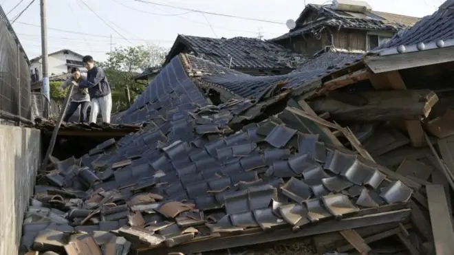 Residents cross over debris of collapsed buildings in Mashiki, south-western Japan. Photo: 16 April 2016