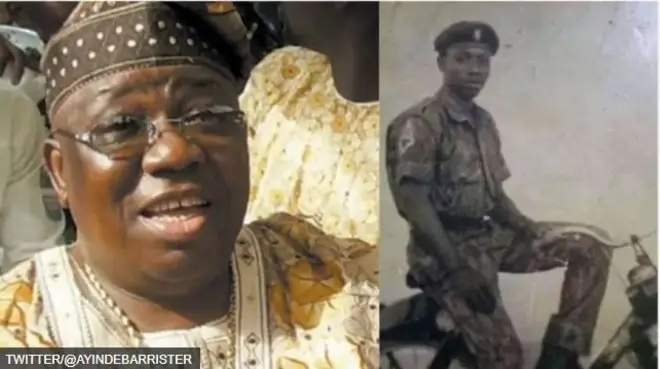 Aworan Sikiru Ayinde Barrister ninu agbada ati ninu aṣọ ṣọja nibi to ti joko sori kẹkẹ.