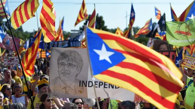 People hold a portrait of ousted Catalan regional president Carles Puigdemont (C) while waving Catalan pro-independence "Estelada" flags and banners during a demonstration at the European Parliament on July 2 , 2019