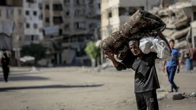 په غزه کې یوه سړي د خپل کور ځينې توکي په شا کړي دي.