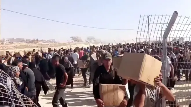 Screengrab of video showing Palestinians carrying aid boxes after storming a distribution site run by the US-backed Gaza Humanitarian Foundation, in Rafah, in the southern Gaza Strip, May 27, 2025