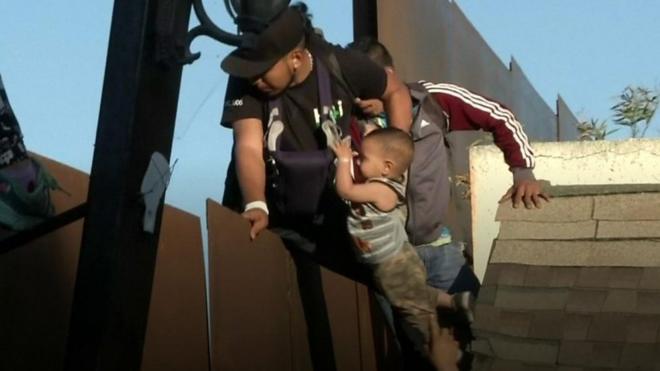 رجل وطفله يستلقان سياجا حدوديا يفصل بين المكسيك والولايات المتحدة، طلبا للجوء، ولكن دورية لحرس الحدود الأمريكي اعتقلته في الحال.