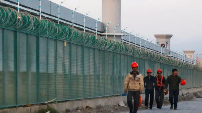 Pekerja melawati kompleks berpagar tinggi yang oleh Beijing dikatakan sebagai 'pusat pelatihan dan pendidikan vokasi' bagi warga di Xinjiang.