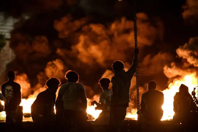 Des personnes regardent des pneus en feu bloquant une rue à Bordeaux, dans le sud-ouest de la France, le 29 juin 2023