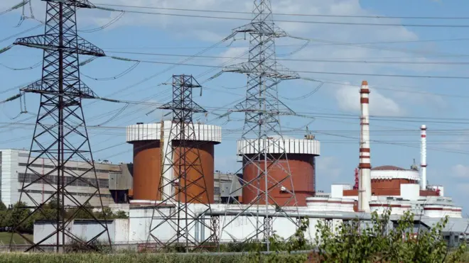 Загальний вид АЕС. Труби станції, стіни паркану, будівлі лінії електропередач.