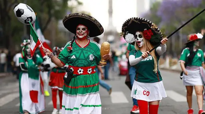Dos mujeres con maquillaje de Catrina y camisetas de la selección de fútbol de México.