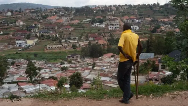 Umugabo ureba agace gatuwemo mu bucucike mu mujyi wa Kigali, gateganye n'inzu zigezweho. Abahatuye bavuze ko ubuyobozi bw'umujyi bushaka kuhabimura ku gahato nta ngurane hagahabwa umushoramari ngo ahubake inzu zigezweho - ibyo umujyi wa Kigali uhakana. (Ifoto yo mu bubiko)