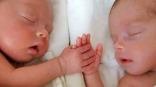 Baby twins holding hands