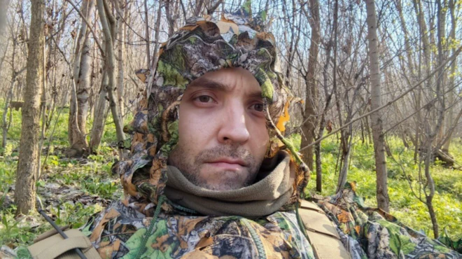 Мужчина в маскировочном костюме в лесополосе