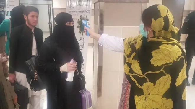 محکمہ صحت کی اہلکار پشاور ہوائی اڈے پر تھرمل سکینر کی مدد سے مسافروں کو چیک کر رہی ہیں۔