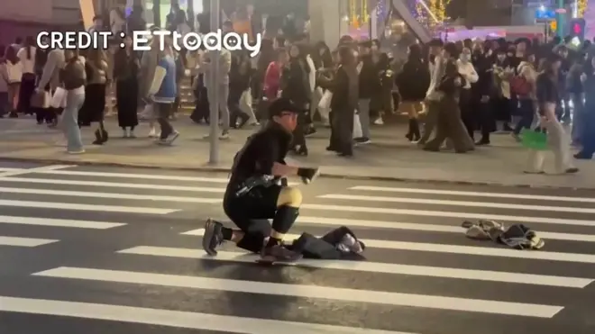 捷运台北车站烟雾弹袭击凶嫌（中）在台北捷运中山站门外马路中央准备投掷更多烟雾弹（台湾ETtoday影片截屏 19/12/2025）