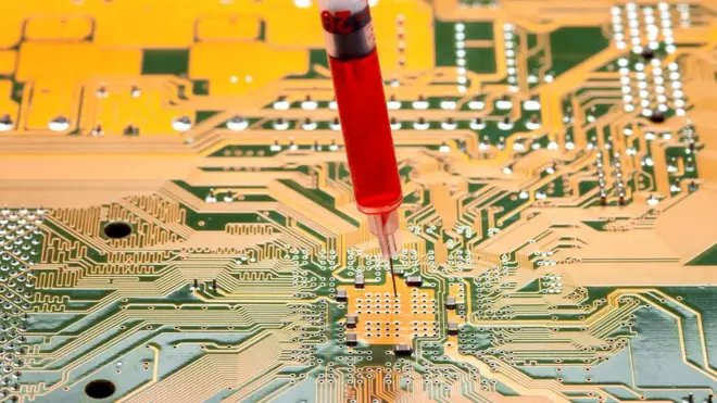 Motherboard with a syringe with needle filled with red liquid