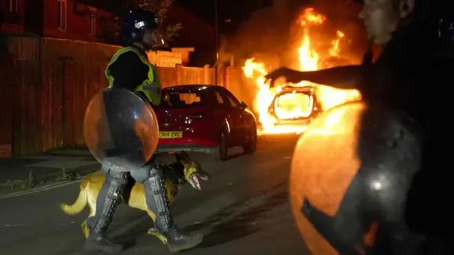 Policial com cachorro passabonus cassinofrente a carro pegando fogobonus cassinoprotesto