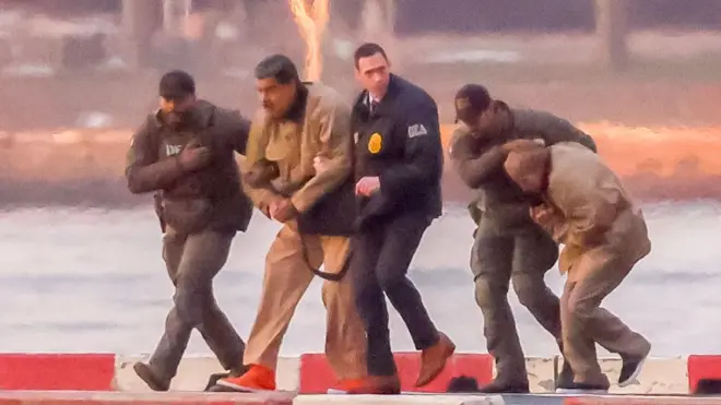 Rettenu par des gardes en uniforme, le président vénézuélien Nicolás Maduro arrive menotté à l'héliport du centre de Manhattan avant sa comparution devant le tribunal fédéral de New York, aux États-Unis, le 5 janvier 2026.