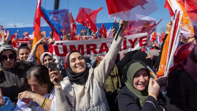 AKP supporters hold party banners and posters of President Erdogan at a rally