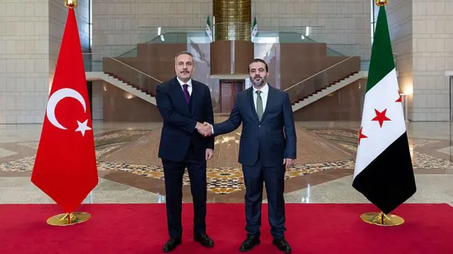 Hakan Fidan ve Esad Hasan Şeybani Türkiye ve Suriye bayrakları önünde tokalaşıyor