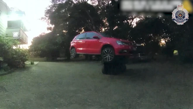 A red car suspended in the air by a forklift