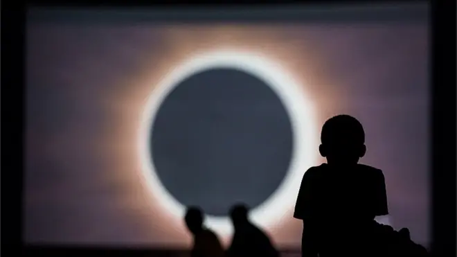 Ребенок смотрит солнечное затмение на экране