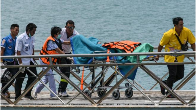 Thai rescue personnel move a passenger on a stretcher at Chalong pier in Phuket on July 6, 2018. Dozens of passengers are missing after a boat capsized as high winds whipped up rough seas off the Thai tourist island of Phuket, officials said late July 5.