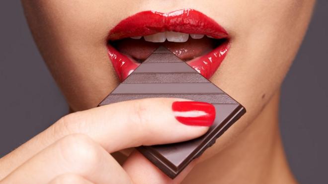 A woman's lips biting a piece of chocolate