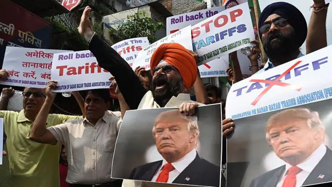Members of Federation of Sadar Bazar Trades Association raise slogans with Donald Trump's photos during a protest against the recent tariffs in New Delhi, India. 印度新德里:薩達爾巴扎爾貿易協會聯合會成員在抗議最近徵收的關稅期間高舉印有唐納德·特朗普照片的口號。