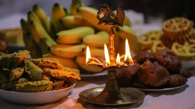 свећњак гори, а на столу су банане и неки слаткиши, колачи