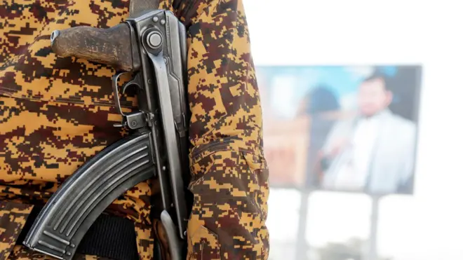 جندي أمن يحرس بالقرب من لوحة إعلانية تصور زعيم الحوثيين عبد الملك الحوثي