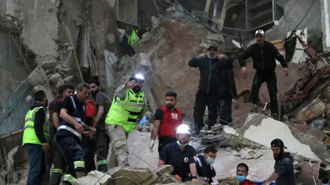 一些救援人员，有的戴着头盔和头灯，有的戴着口罩，在被摧毁建筑物的废墟中工作。