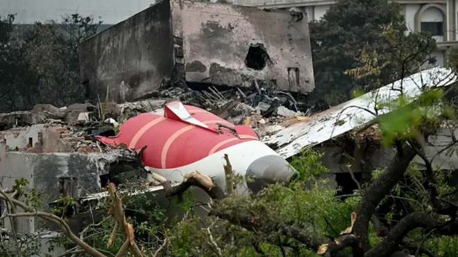 لاشه یک هواپیما در میان ساختمان ویرانه و درختان شکسته