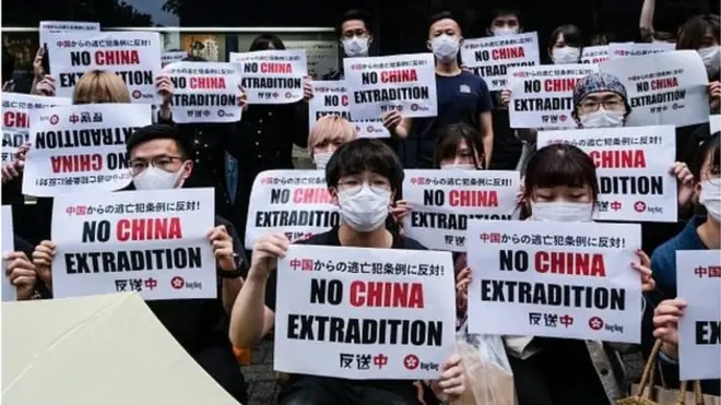 ผู้ประท้วงถือป้ายข้อความต่อต้านร่างกฎหมายส่งผู้ร้ายข้ามแดน เมื่อวันที่ 12 มิ.ย.