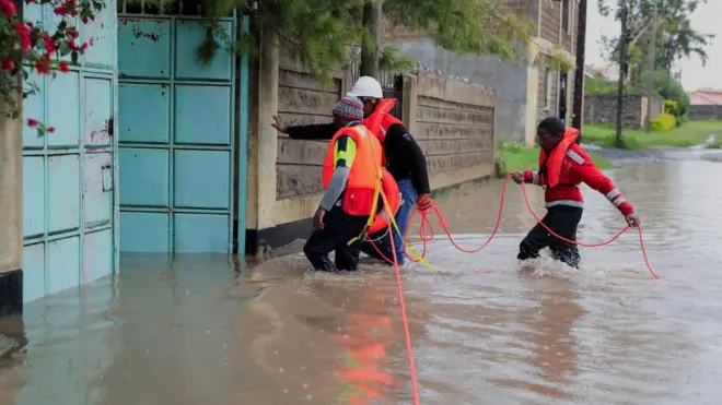 Kenya Red Cross staff wade through flood waters to reach residents trapped in their homes after a river burst its banks amid heavy rainfall - in Kajiado County, Kenya, May 1, 2024