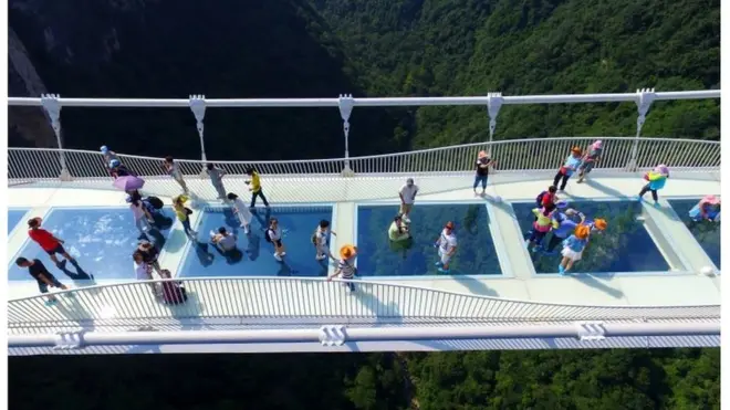 Visitors walk across a glass-floor suspension bridge in Zhangjiajie in southern China's Hunan Province Saturday, Aug. 20, 2016