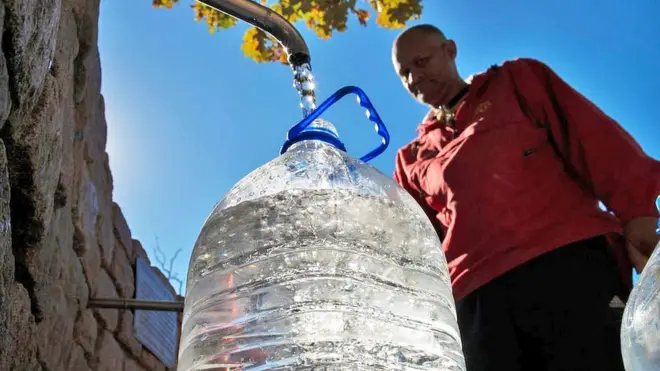 Man filling water flagon from tap