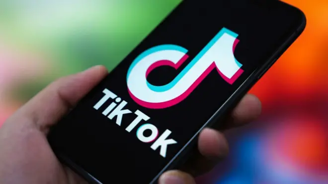 the TikTok logo is displayed on the screen of a smartphone