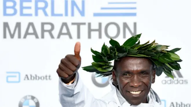 Eliud Kipchoge sur le podium du marathon de Berlin, une couronne de laurier autour de la tête