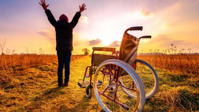 Mujer que se levanta de una silla de ruedas