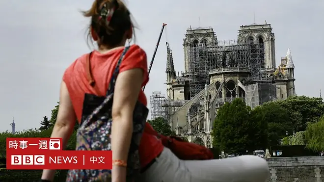 一名女遊客坐在塞納河彼岸堤圍上仰望被焚毀的聖母院（22/4/2019）