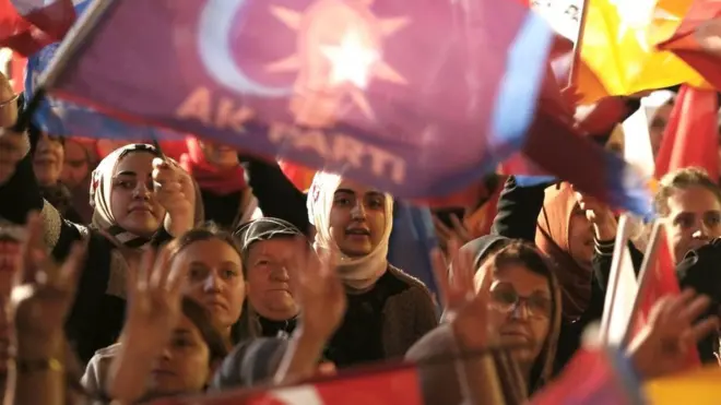Supporters wave flags and banners as Turkish President and presidential candidate Recep Tayyip Erdogan makes an address